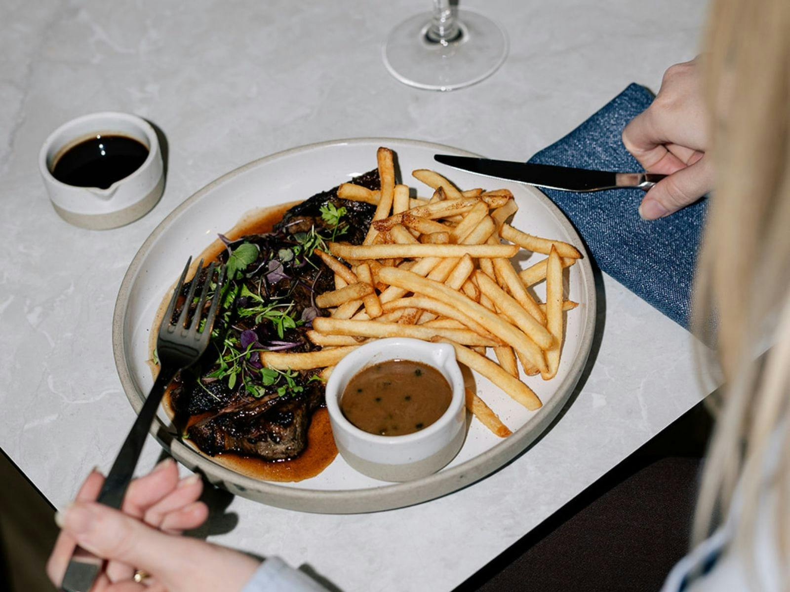 Steak frites on a table with glass of red wine