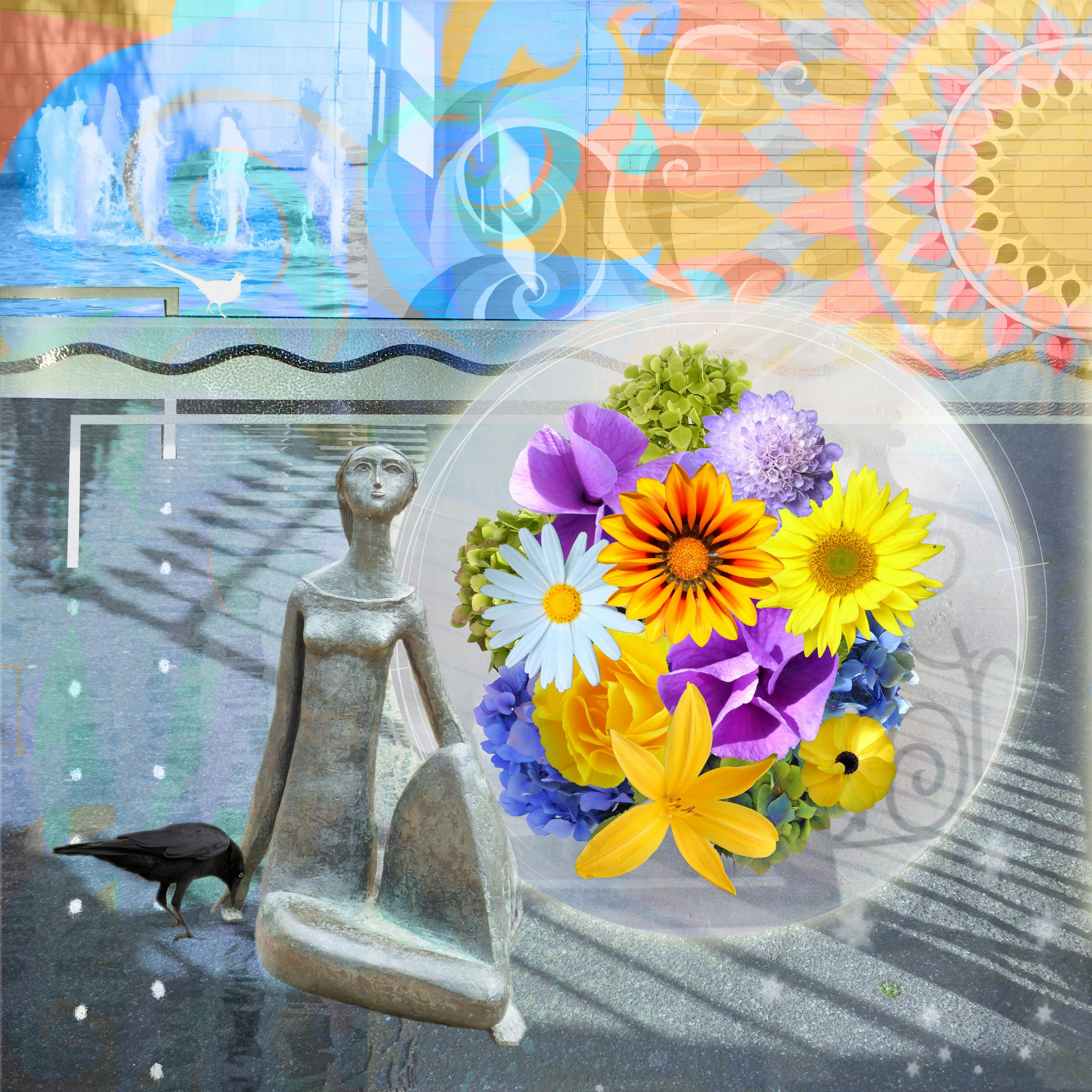 a stone sculpture of a person looking up next to a variety of yellow, purple, white and blue flowers