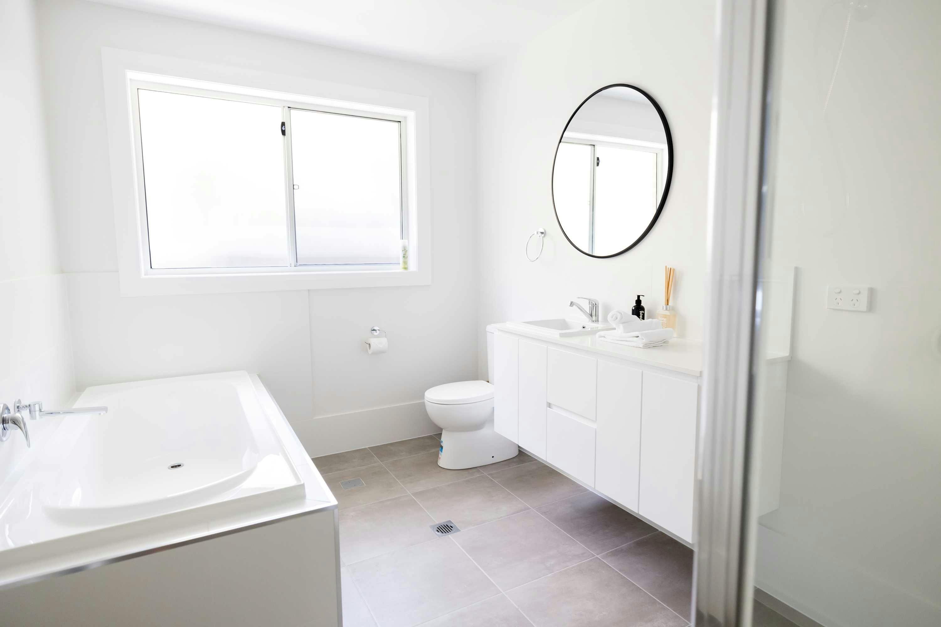 White bathroom with a bath, toilet, vanity and shower