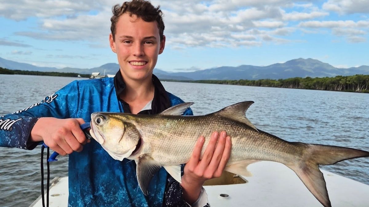Young Cairns angler holding a salmon with Gone Fishing Cairns