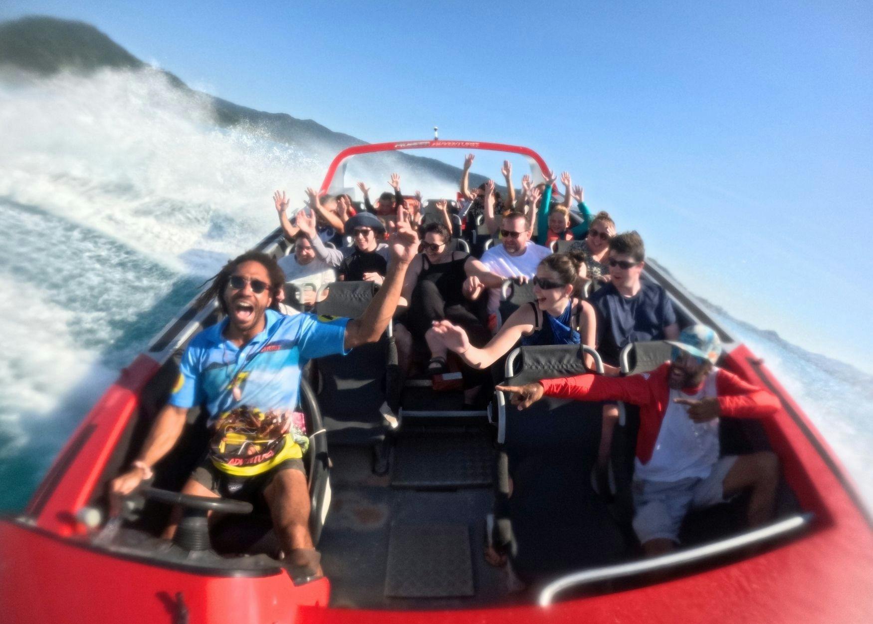 Guests on Jetboat with hands up in excitement. Jet boat is in mid-spin.