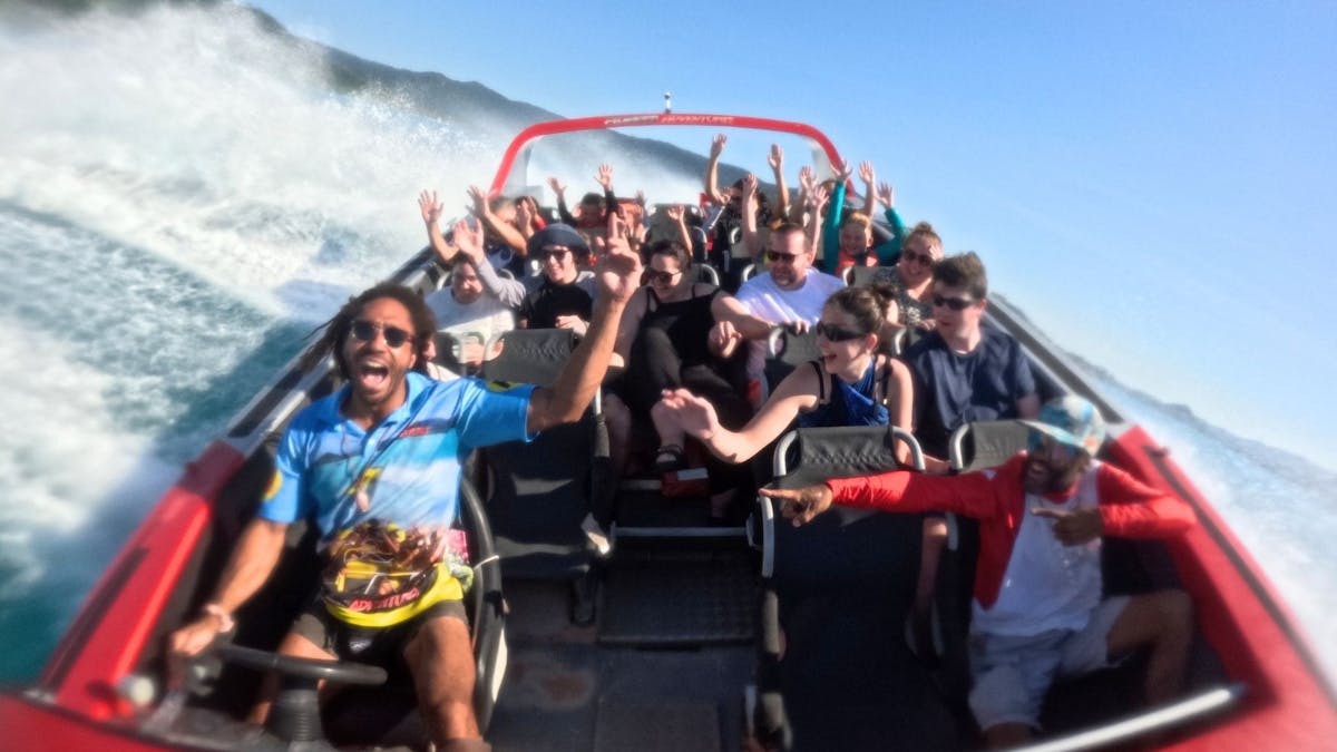 Guests on Jetboat with hands up in excitement. Jet boat is in mid-spin.