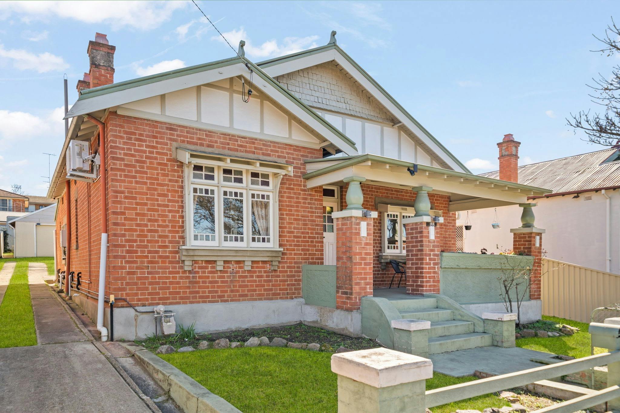 緑のディテールが施されたレンガ造りの家。家の横には私道があります。