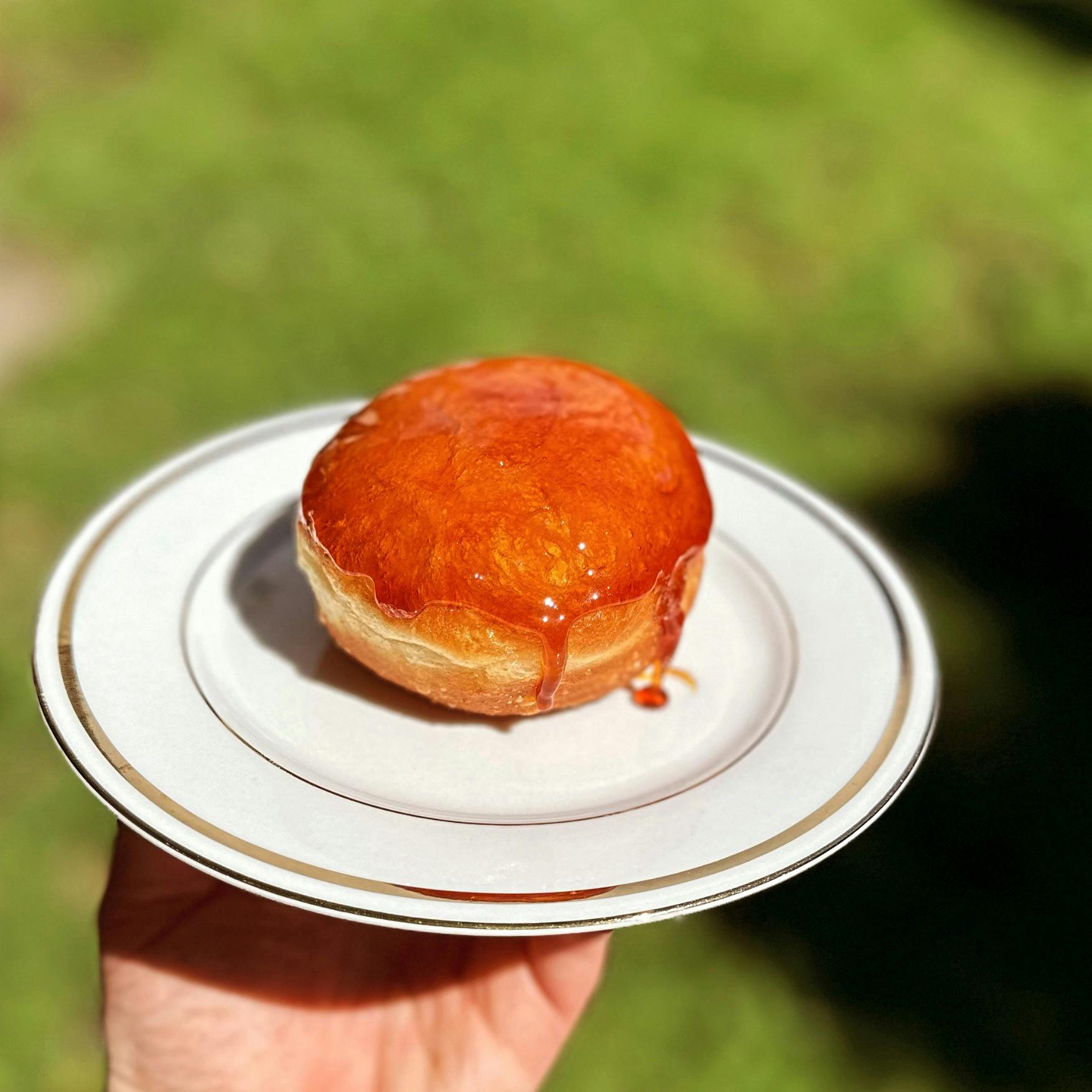 A doughnut covered in hard toffee is sitting on a plate