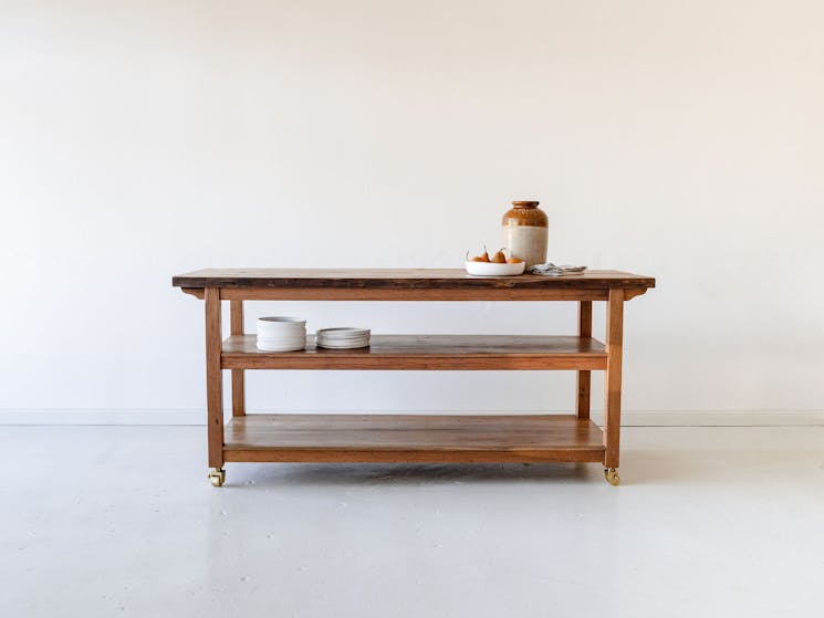A reclaimed timber kitchen island bench made from recycled Australian hardwood with brass castors.