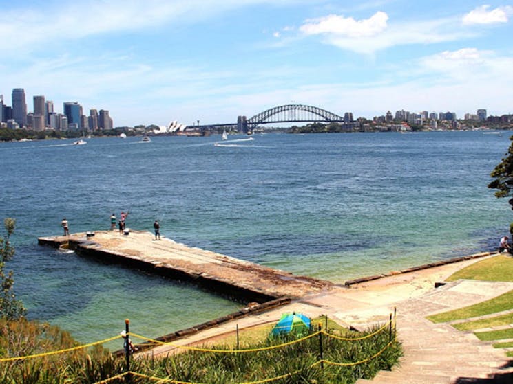 A small concrete jetty overlooking Sydney Harbour with Sydney Harbour Bridge in background