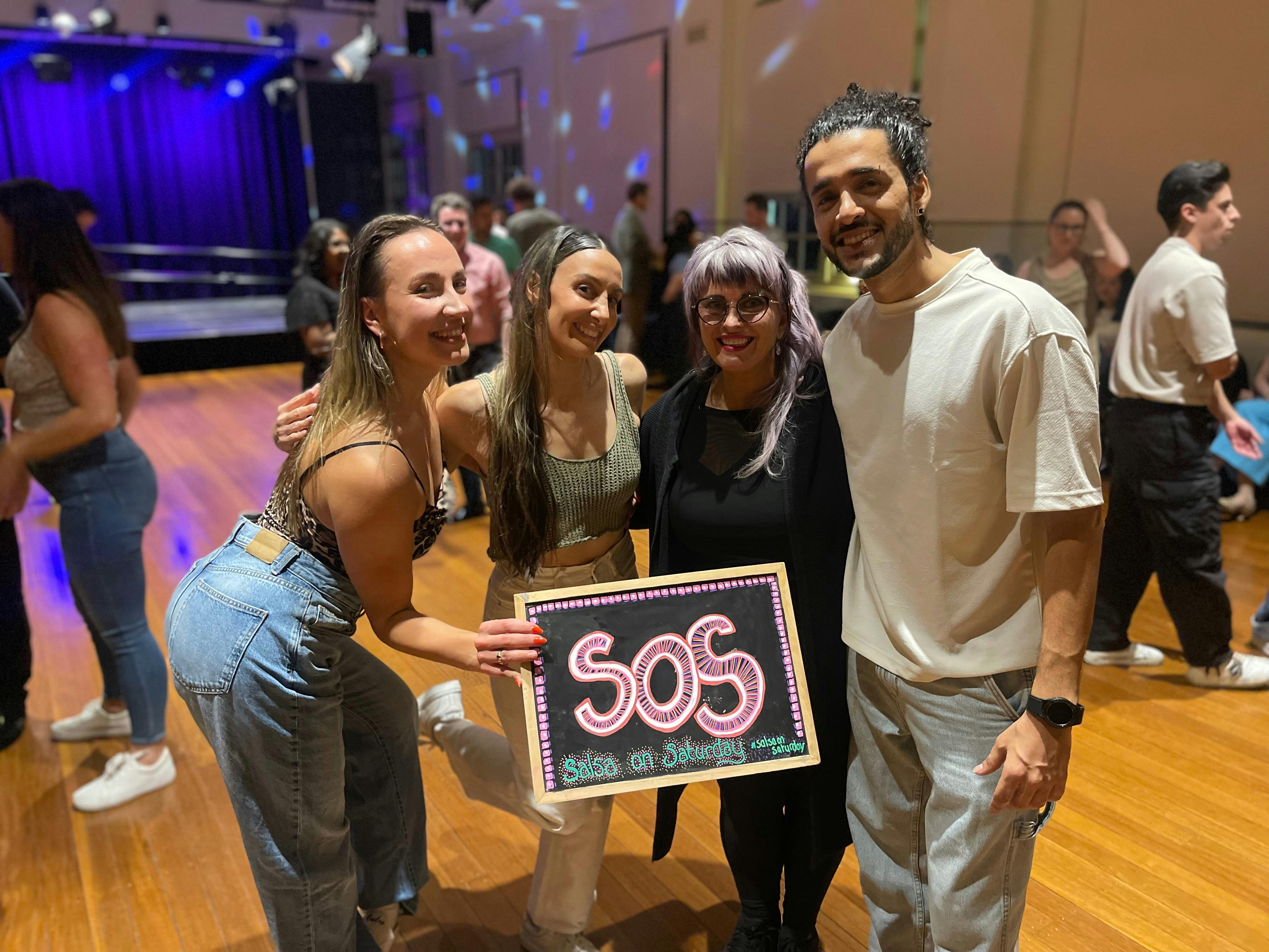 SOS X MoveMe with guest instructors.- 4 people holding the SOS blackboard.