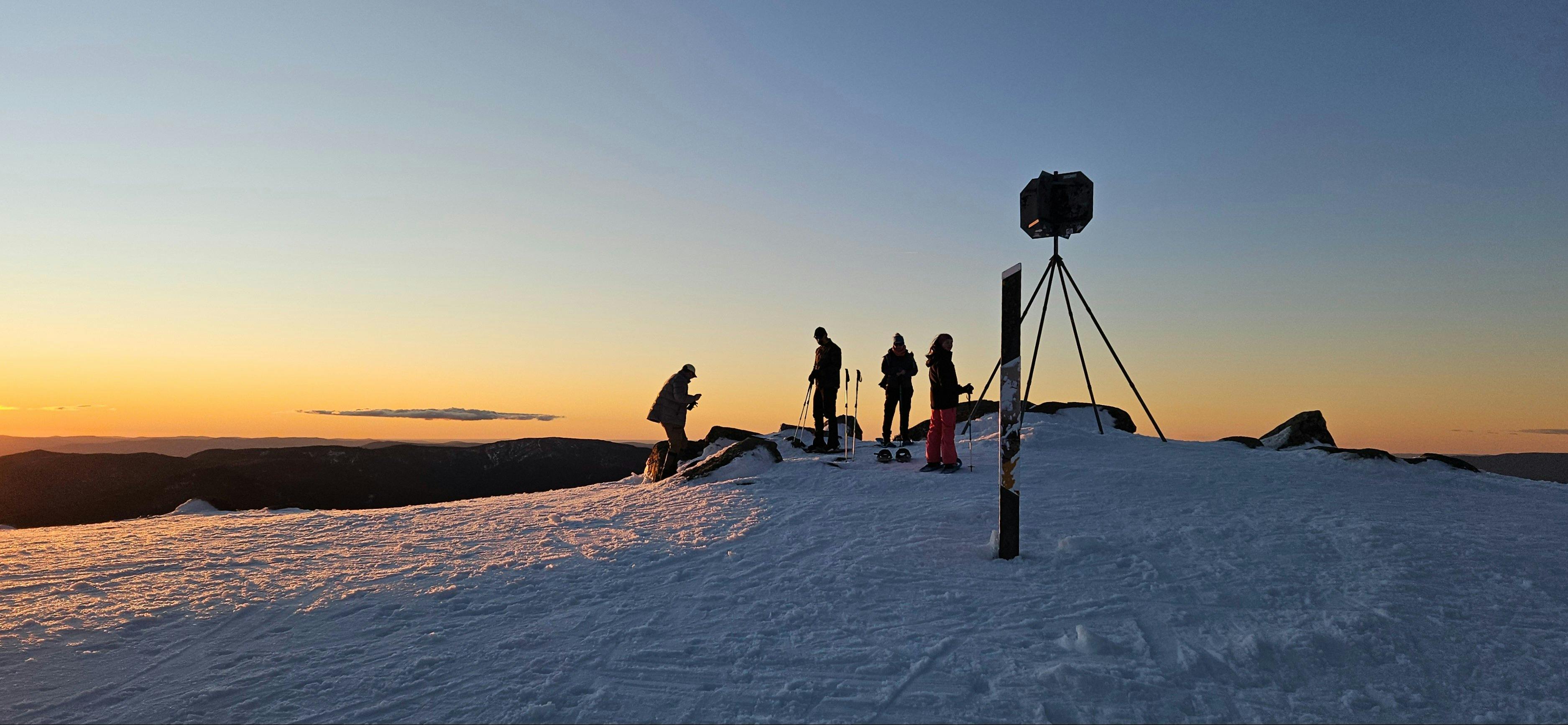 Hikers watching winter sunset from the summit of Mt Stirling
