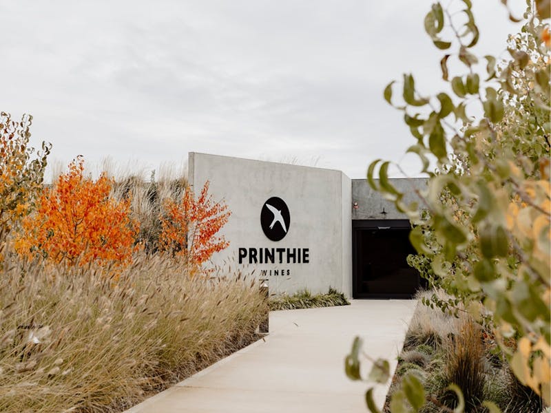 Front Door of Printhie Wines Cellar Doorr showing the garden that includes tress and grasses