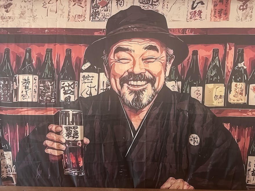 poster on wall of older Japanese mand with gret and black beard smiling holding a glass of saki