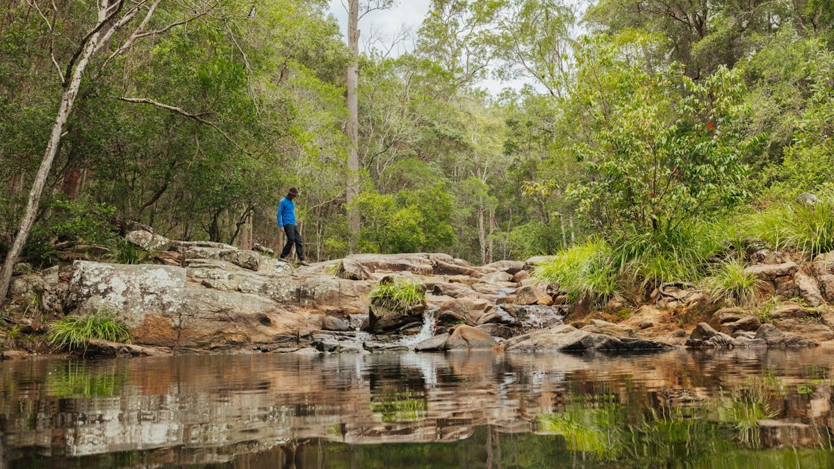 A guy walking across some rocks