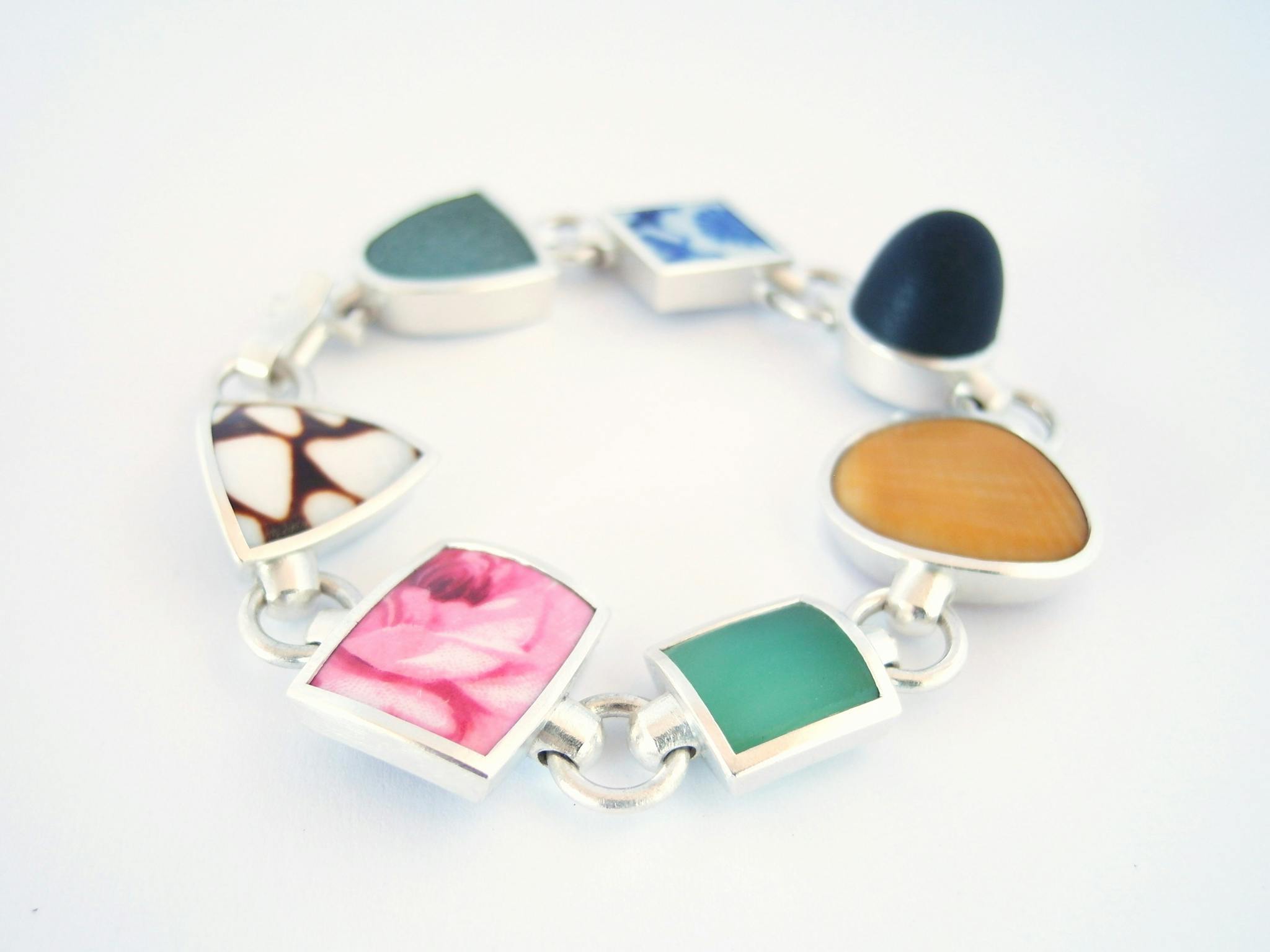 Hand-made silver bangle by Marcus Foley set with glass, pebble, porcelain and shell.