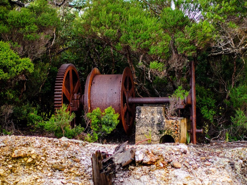 Rusted mine winch perched on the edge of mined land with sharp drop off