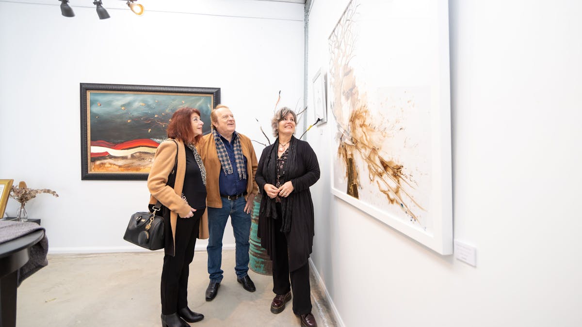three people enjoying looking at large artworks in a private gallery three people enjoying looking at large artworks in a private gallery