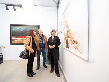 three people enjoying looking at large artworks in a private gallery three people enjoying looking at large artworks in a private gallery