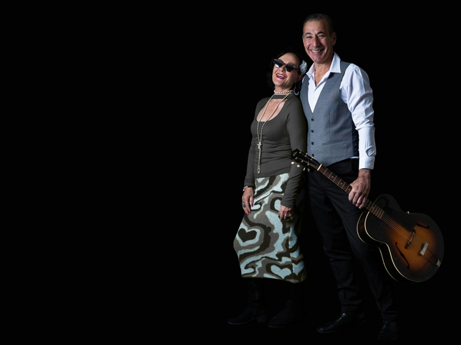 A man and a women holding a guitar and microphone