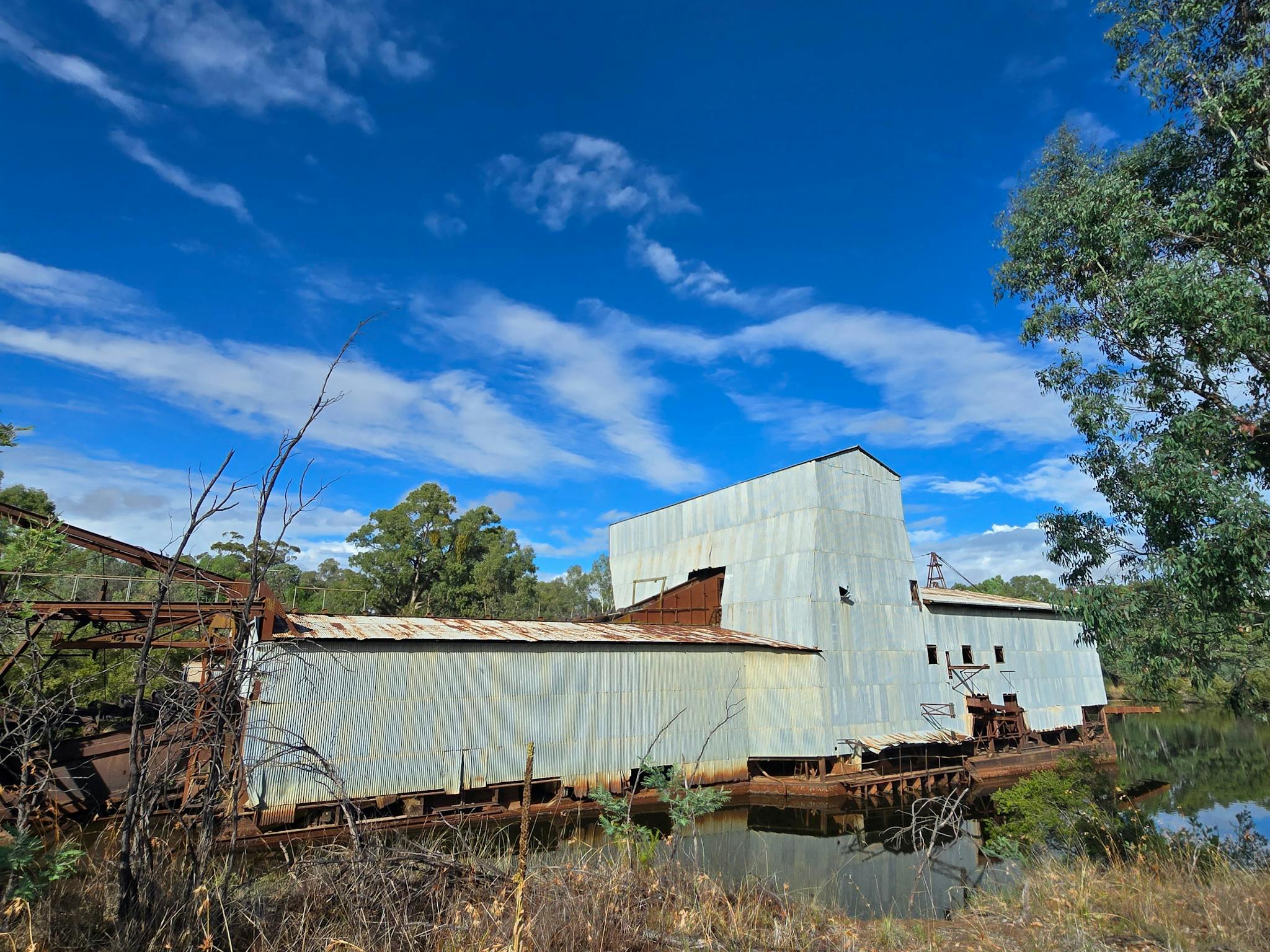 A photograph of the Eldorado Dredge, a massive, rusting gold mining dredge, sits partially submerged