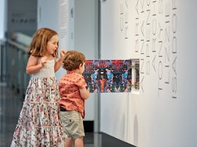 Two children open a cupboard with an art installation inside