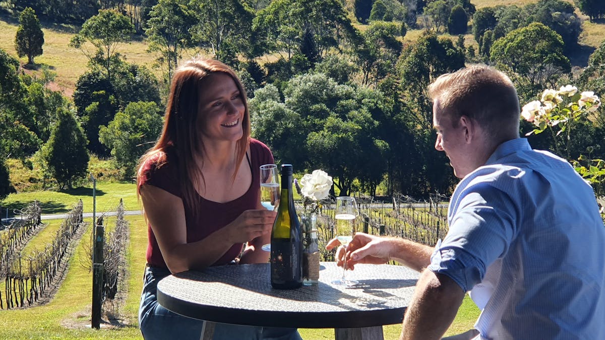 couple sipping wine with winery backdrop