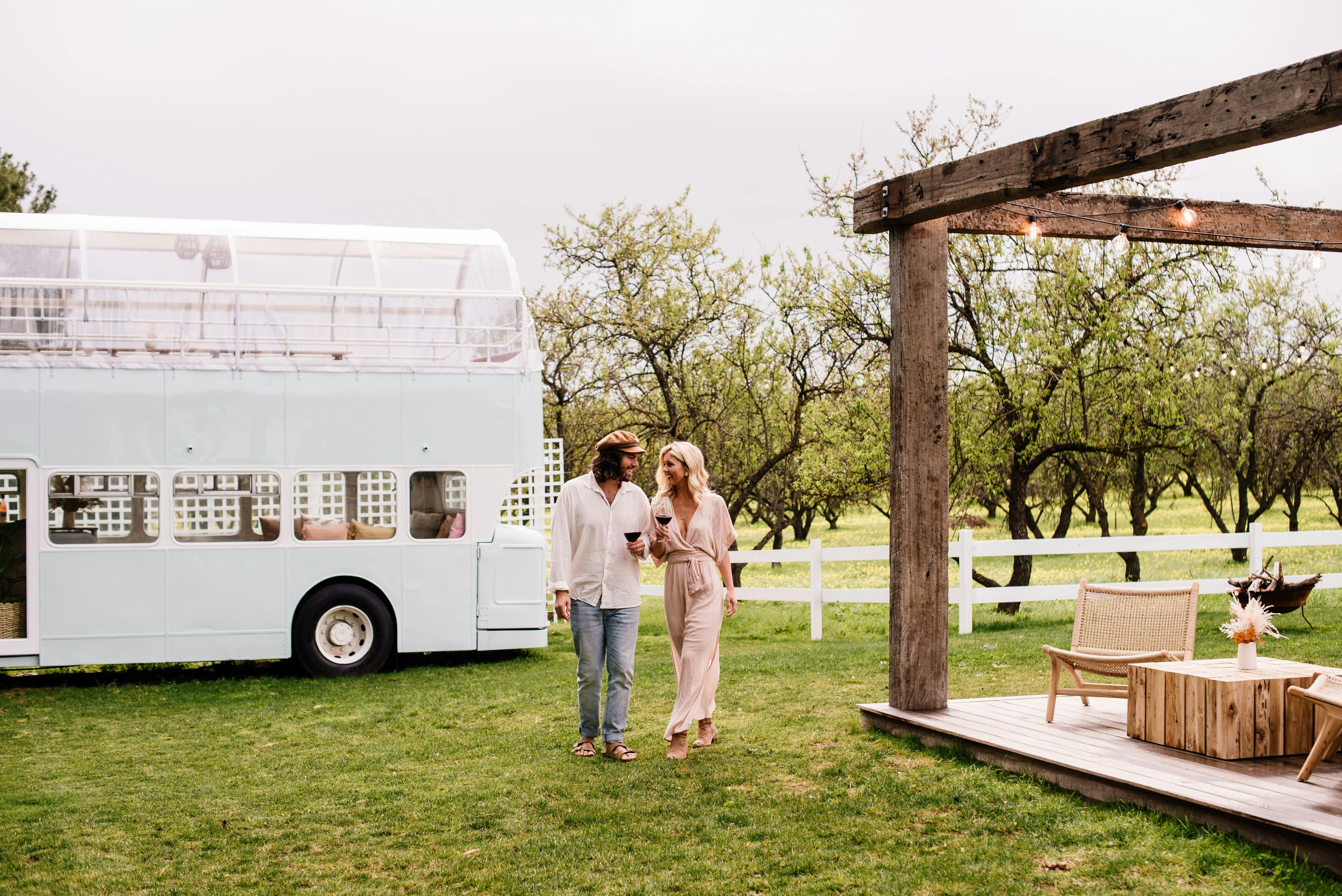 Two people enjoying a wine with the bus in the background of Down the Rabbit Hole on a wine tour