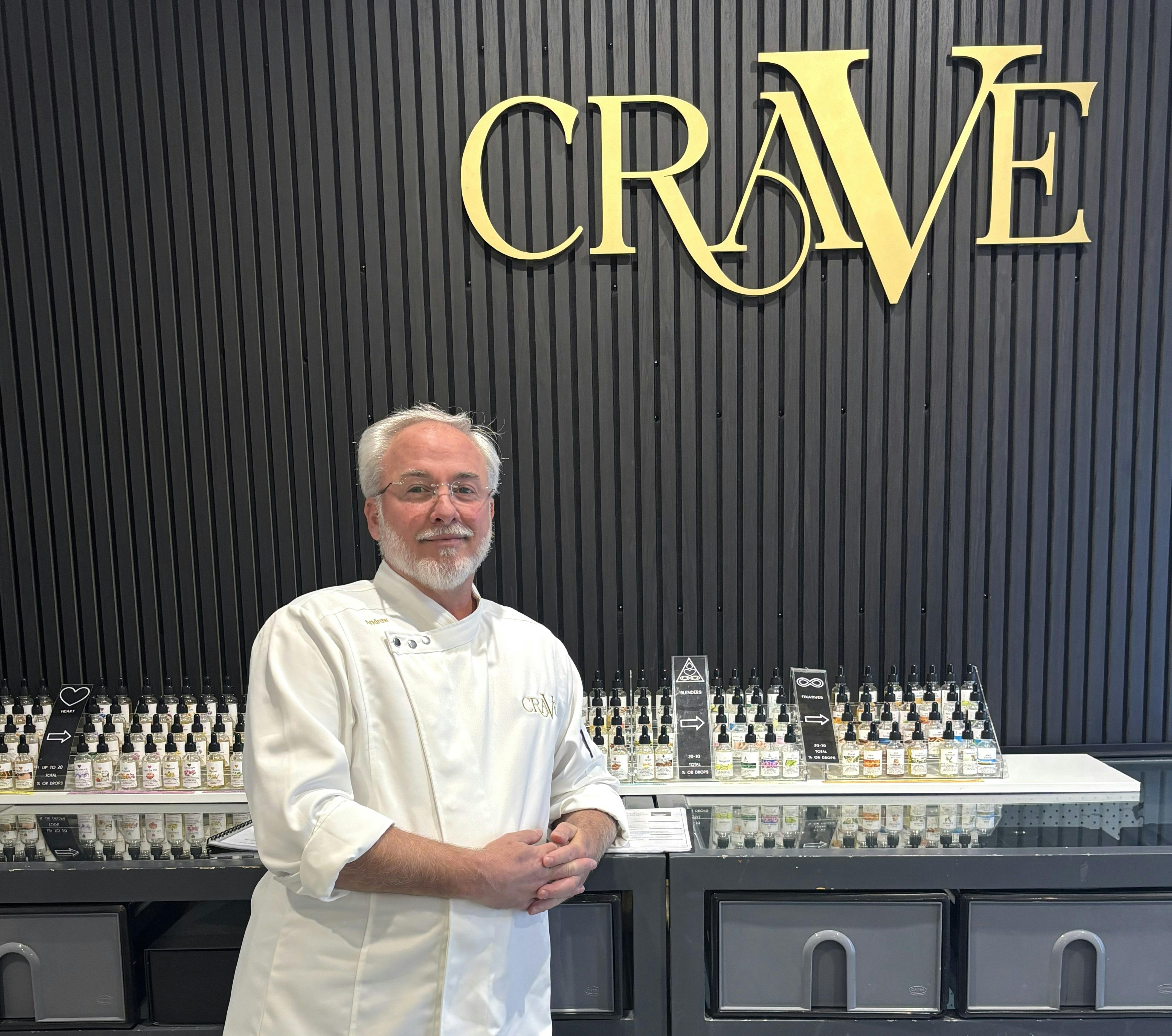Perfumery teacher standing in front of impressive line-up of raw materials
