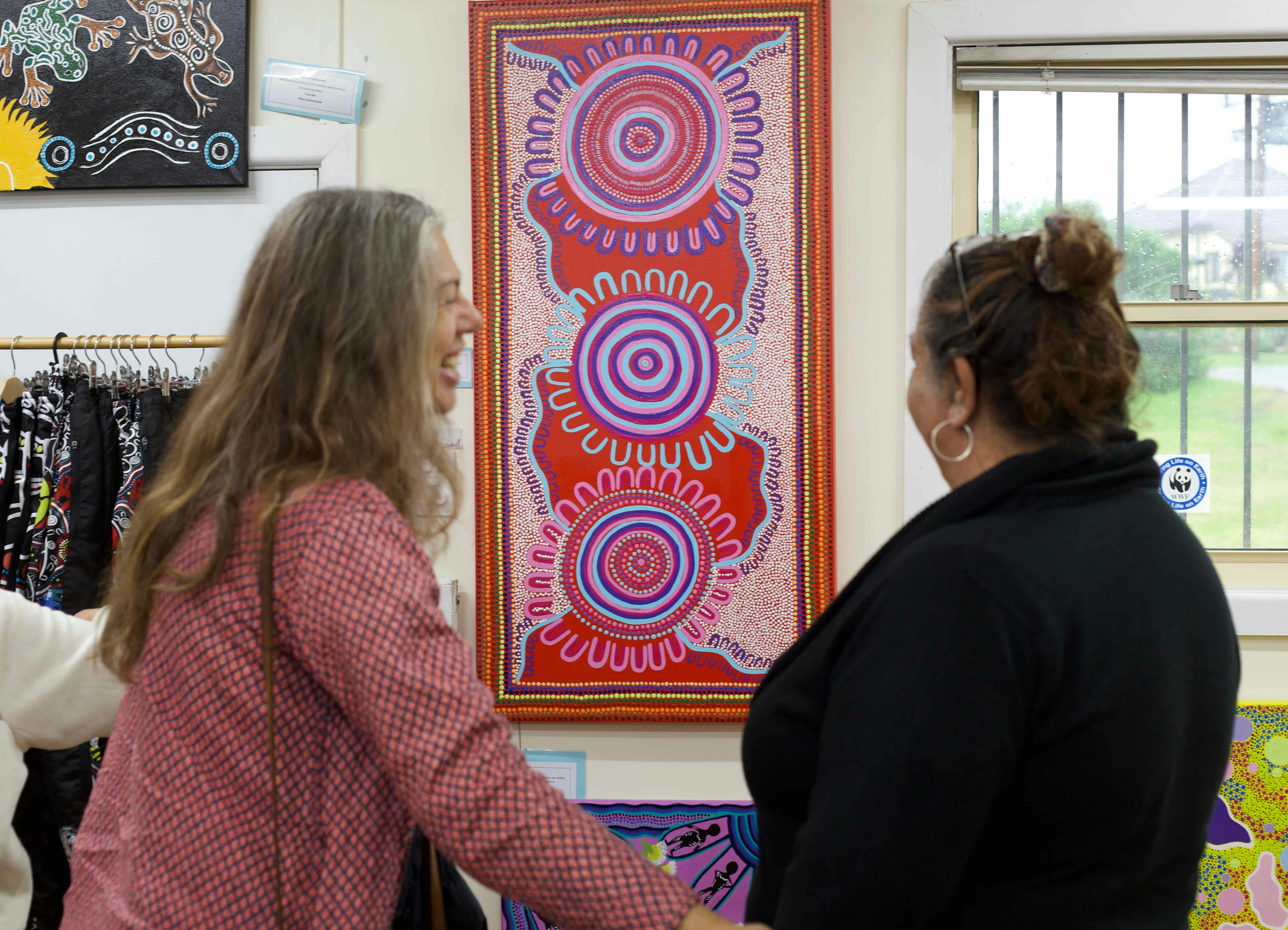 Two women looking at a painting on the wall