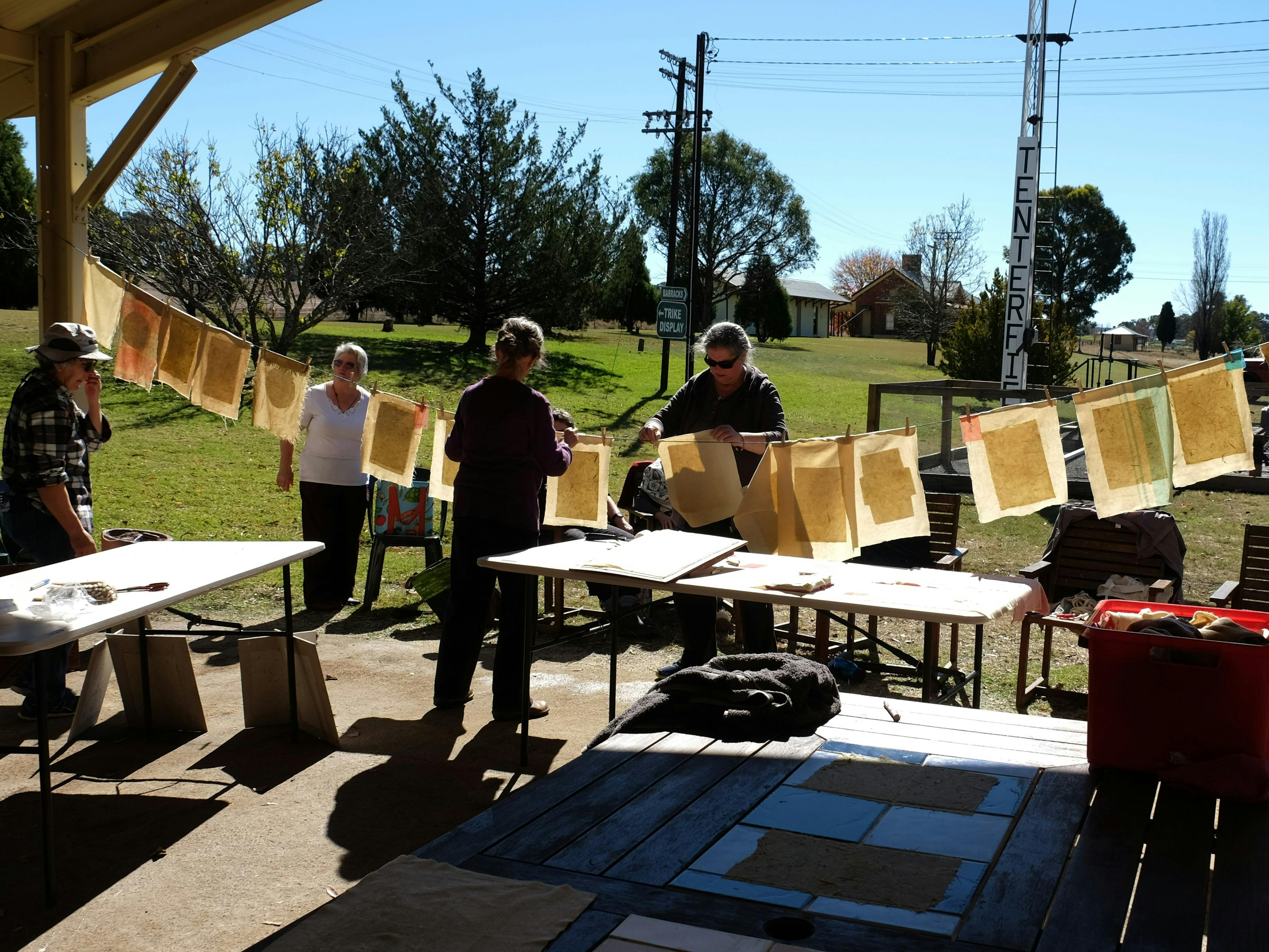 Women hanging pieces of handmade paper on a line in the sunshine