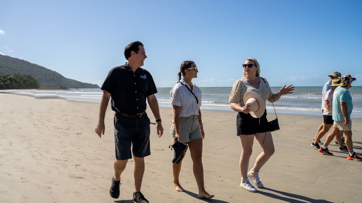 Driver guide from Tropic Wings walking with group of passengers on the beach at Cape Tribulation
