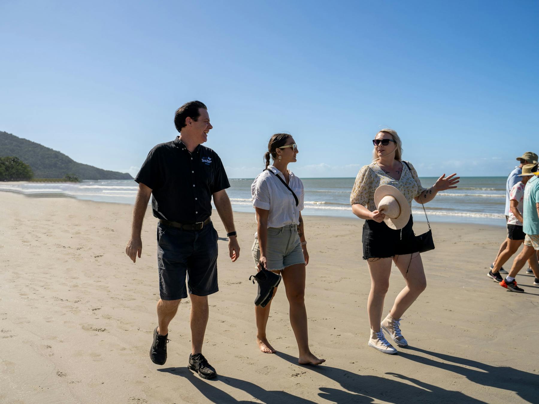 Driver guide from Tropic Wings walking with group of passengers on the beach at Cape Tribulation