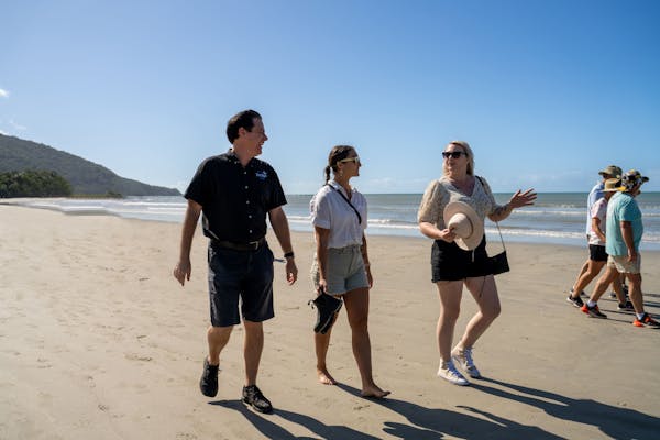 Driver guide from Tropic Wings walking with group of passengers on the beach at Cape Tribulation