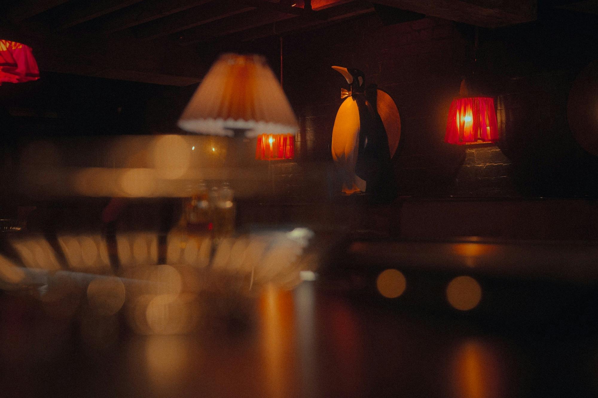 Atmospheric, low-lit venue interior with a large penguin statue at the centre