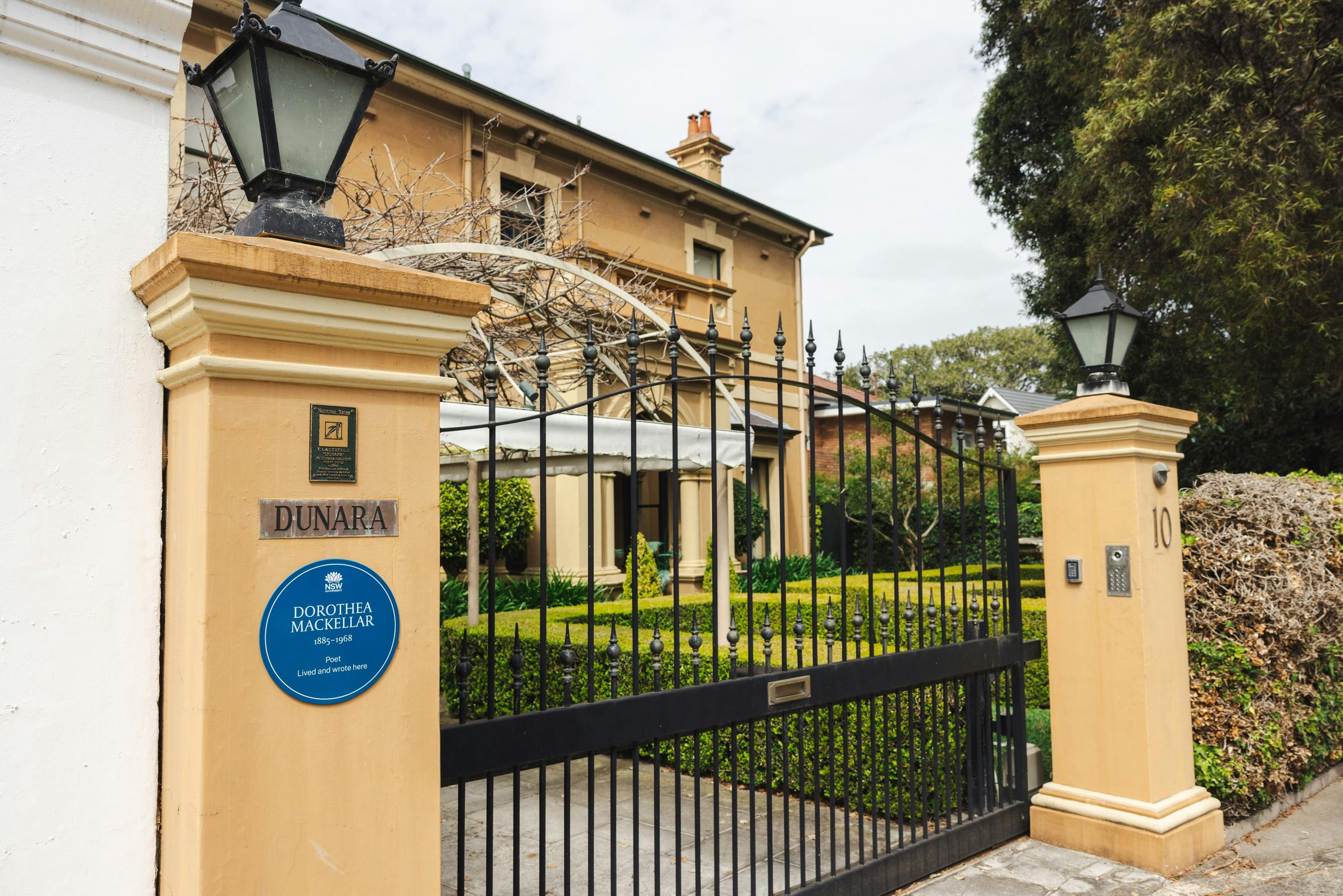 Blue plaque on fence "Dunara" written above, driveway gate, 2-level Georgian mansion in background