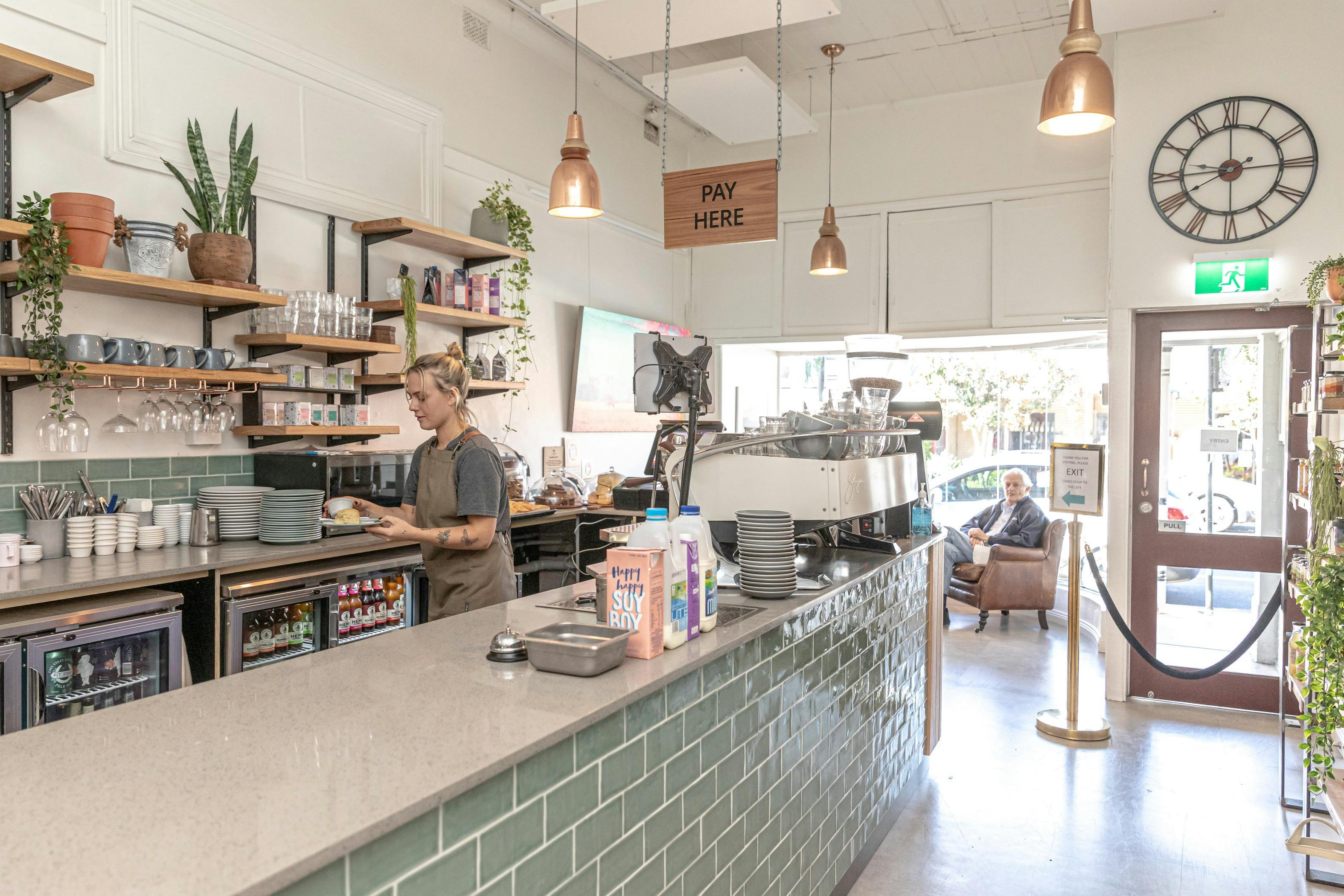 陳列棚、植物、ケーキを準備するウェイトレスと緑のタイル張りのバー