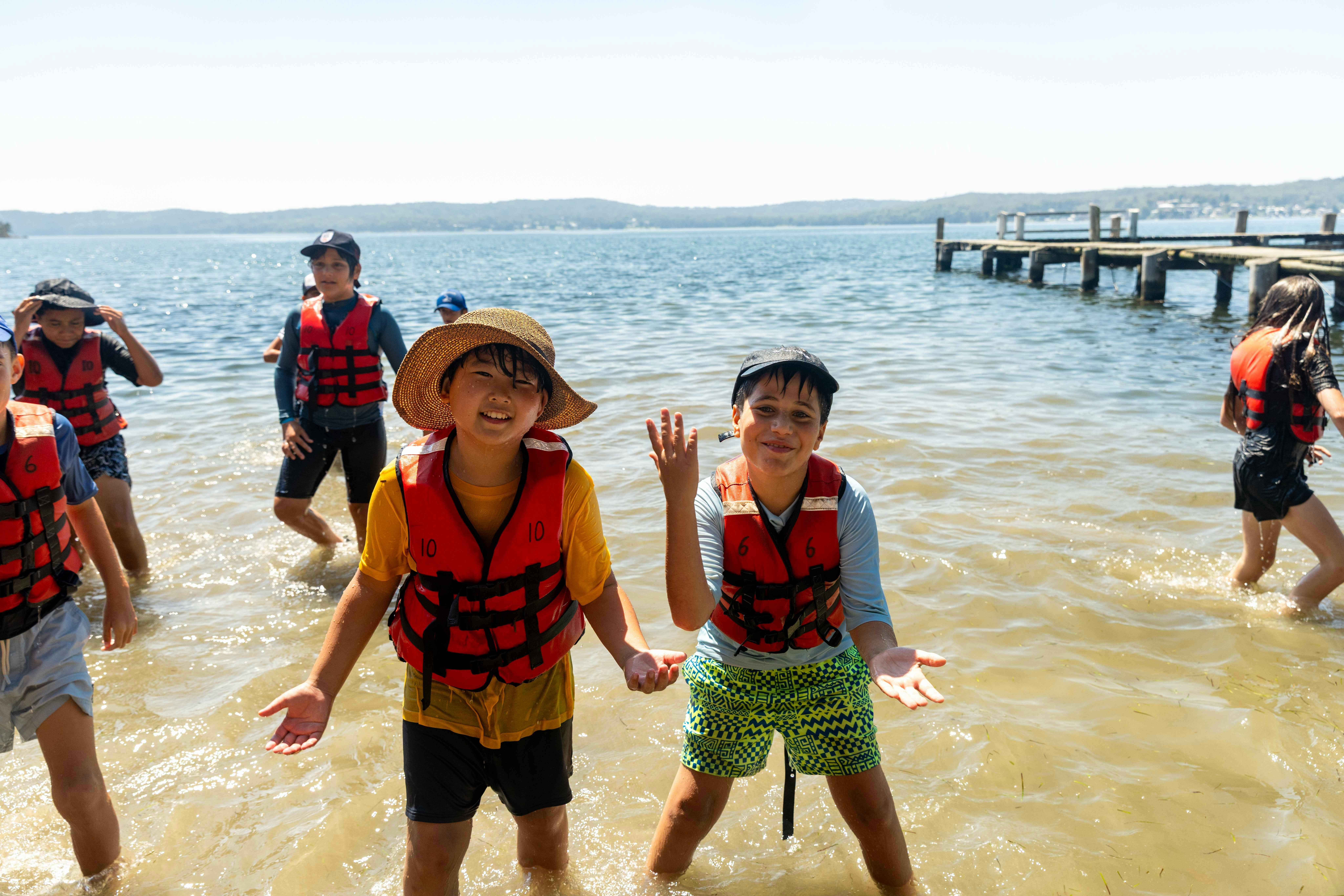 Two children in life jackets at the beach