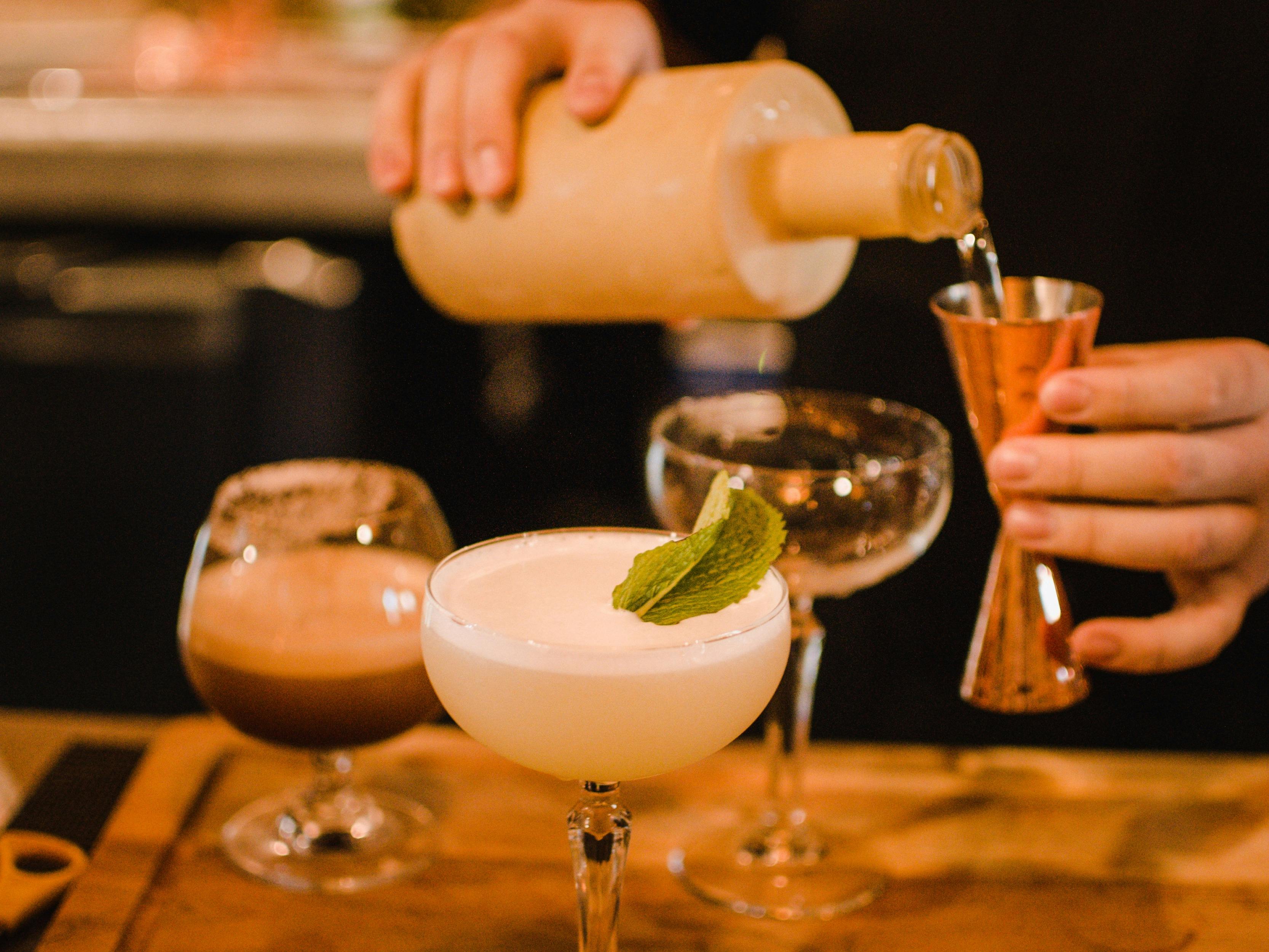 Pouring cocktails using a copper cocktail jigger.