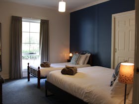 Queen size bed and a single bed in a room with a blue wall