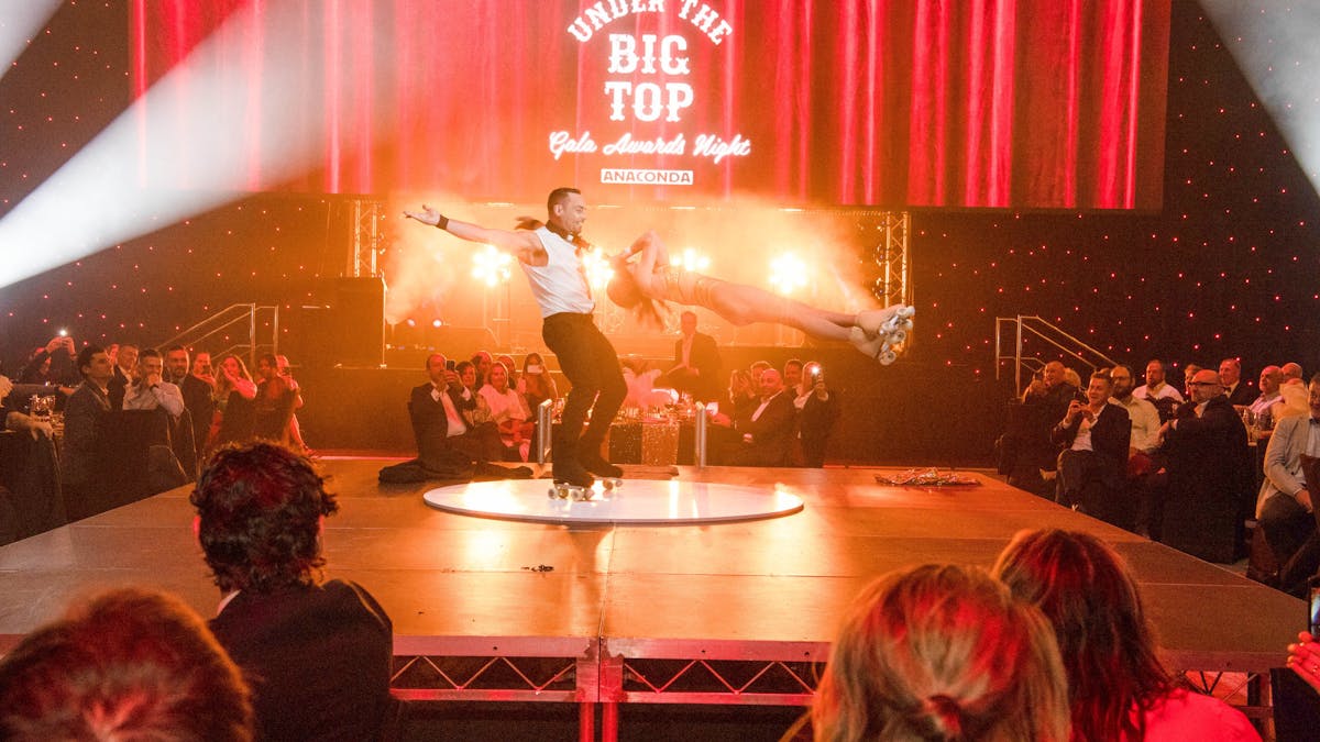 Image of a man and a woman roller-skating on a stage in front of guests at a corporate event