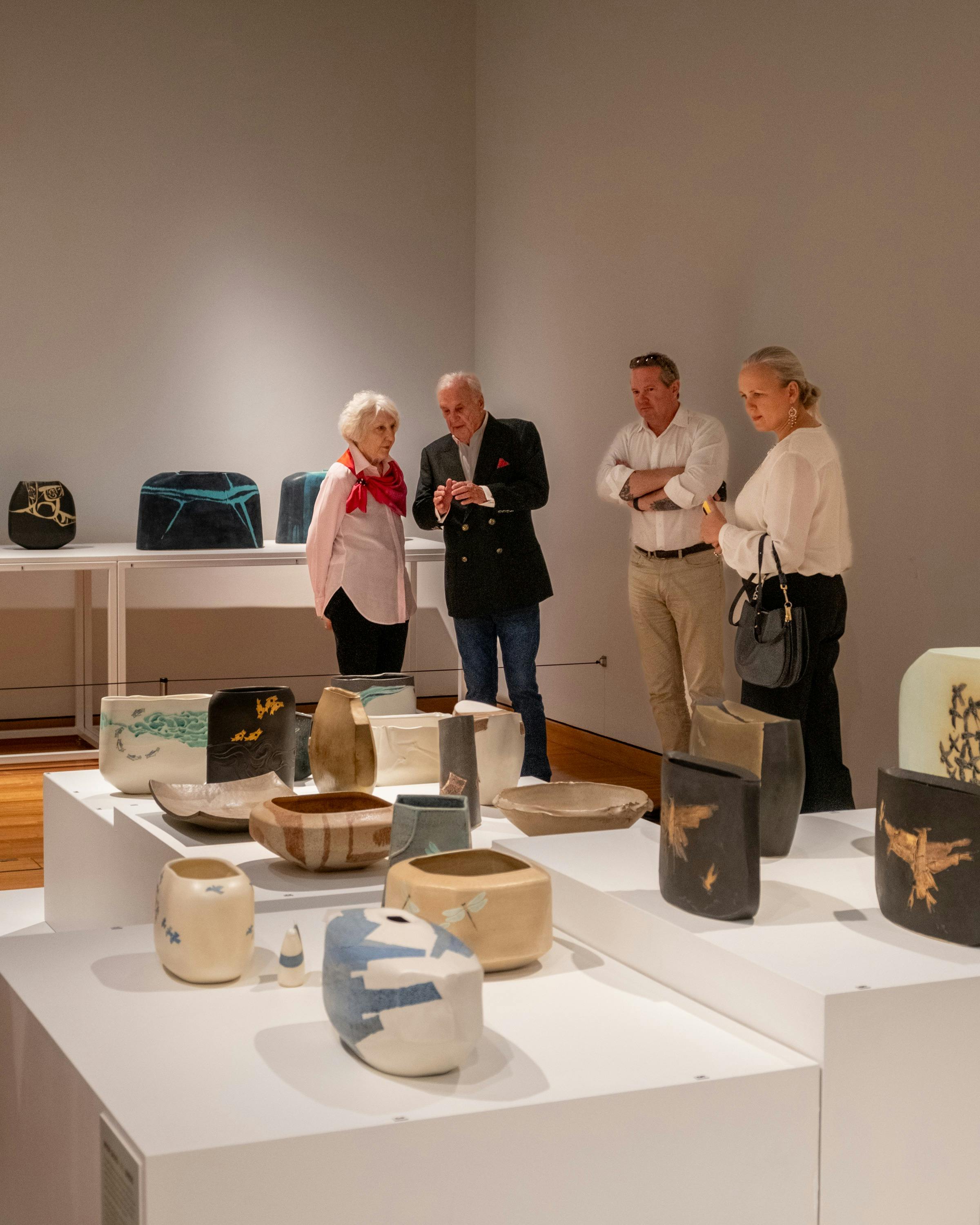 Four people examine the ceramic works of Hiroe Swen