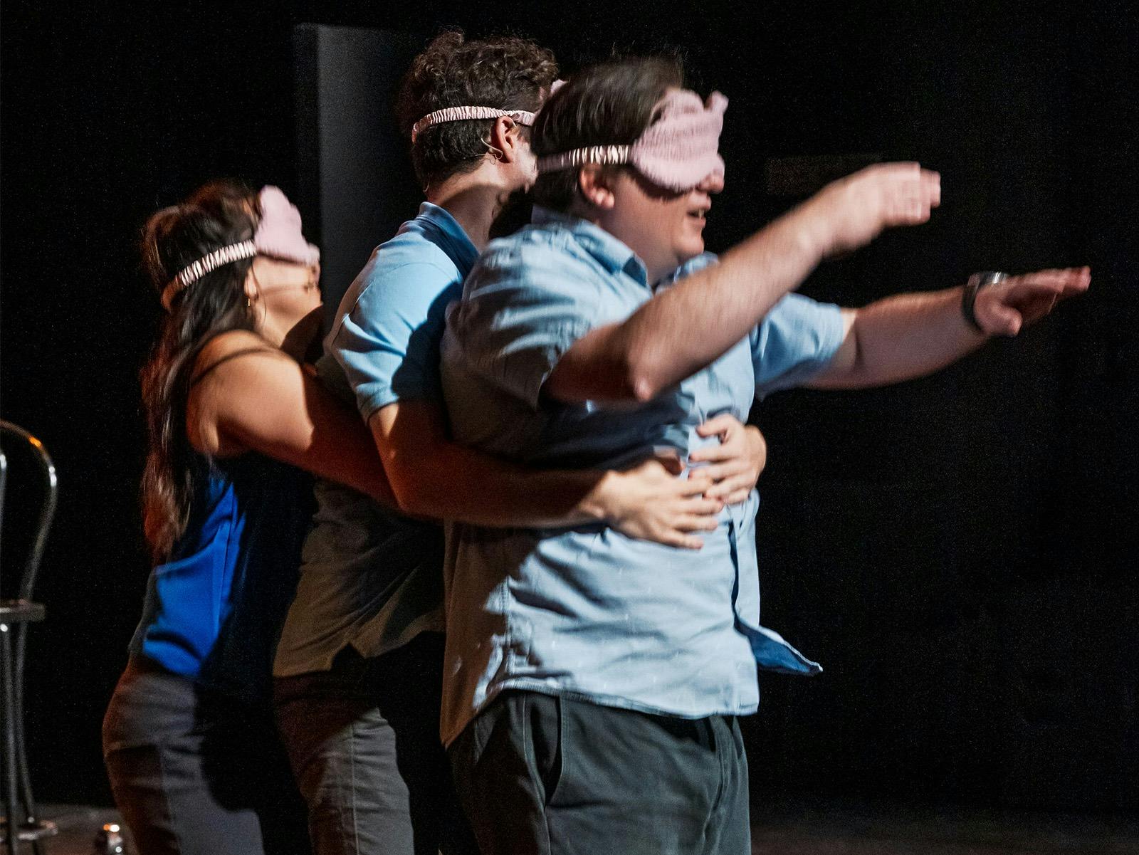 Three improv comedians playing a comedy game with blindfolds in a three-person Heimlich