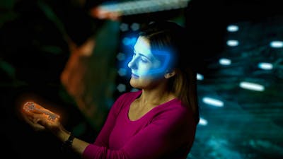 Lady with glowing VR headset looking at glowing key in escape room