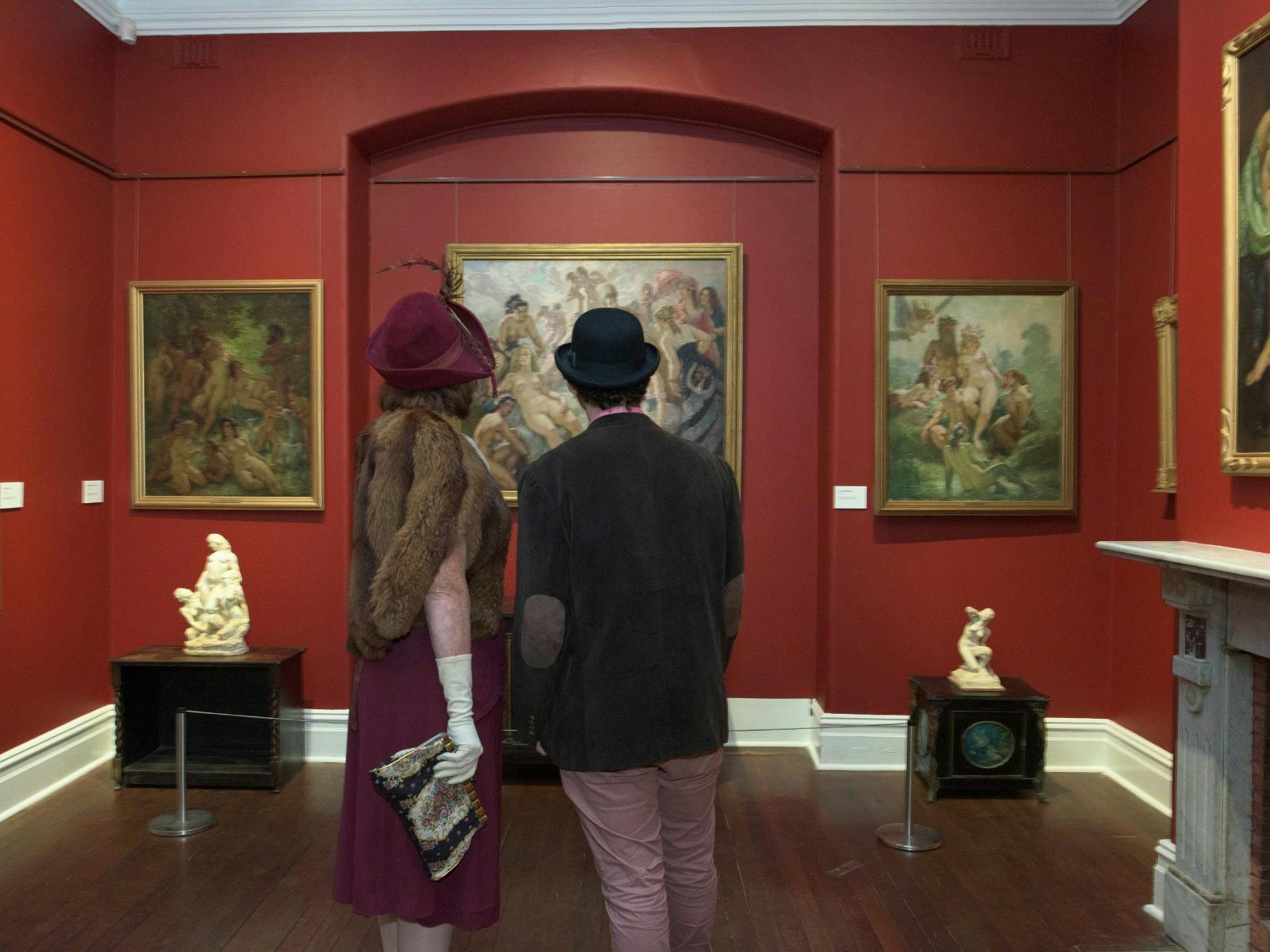 A couple stands with their back to the camera, looking at art
