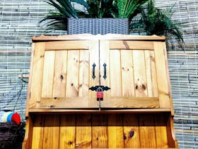 Polished pine double door cupboard framed by bamboo plants and a toucan