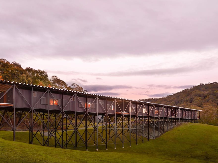 A long wooden structure spans 160m across a grassy gully with purple twilight skies behind