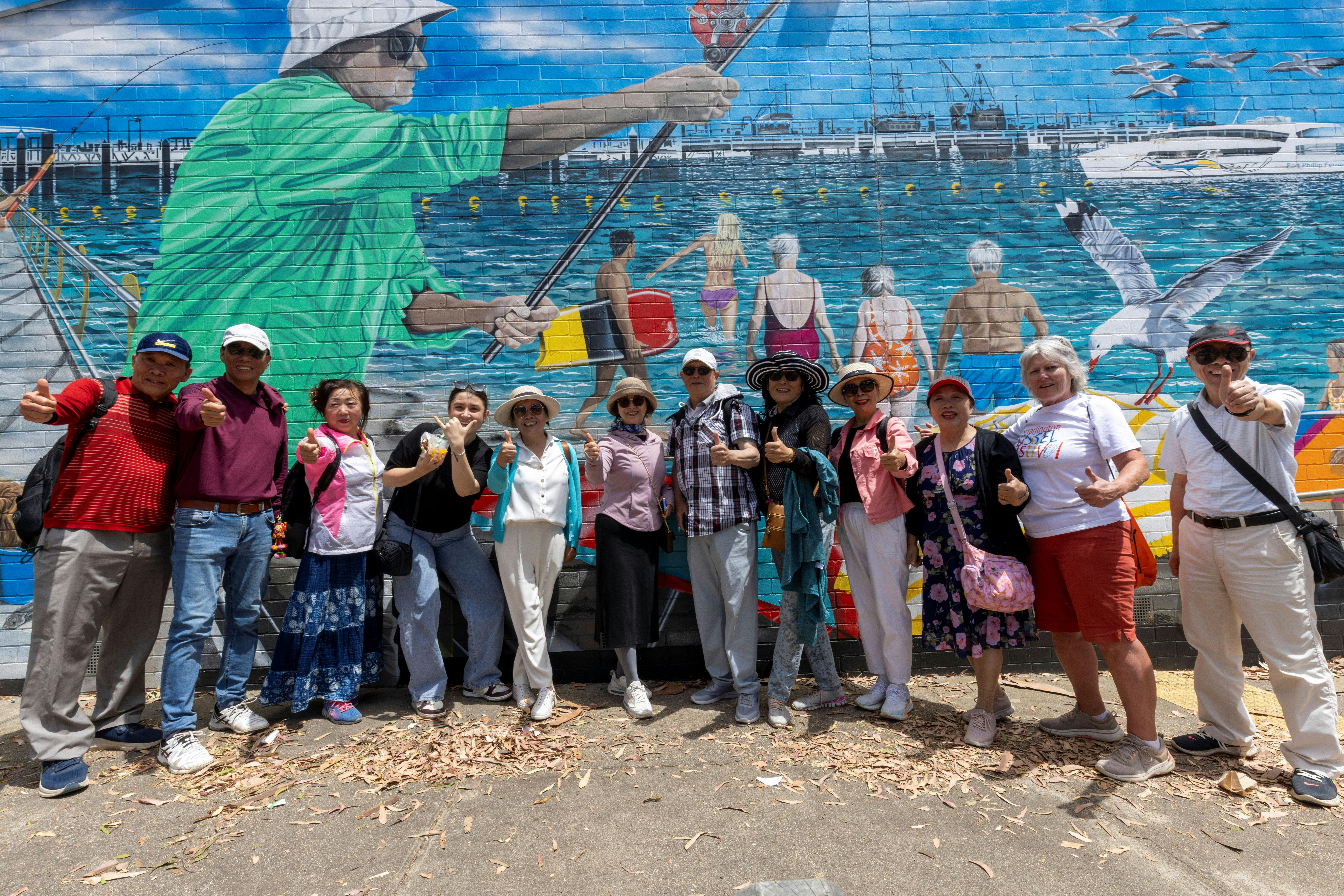Group of international visitors standing in front of a bright mural