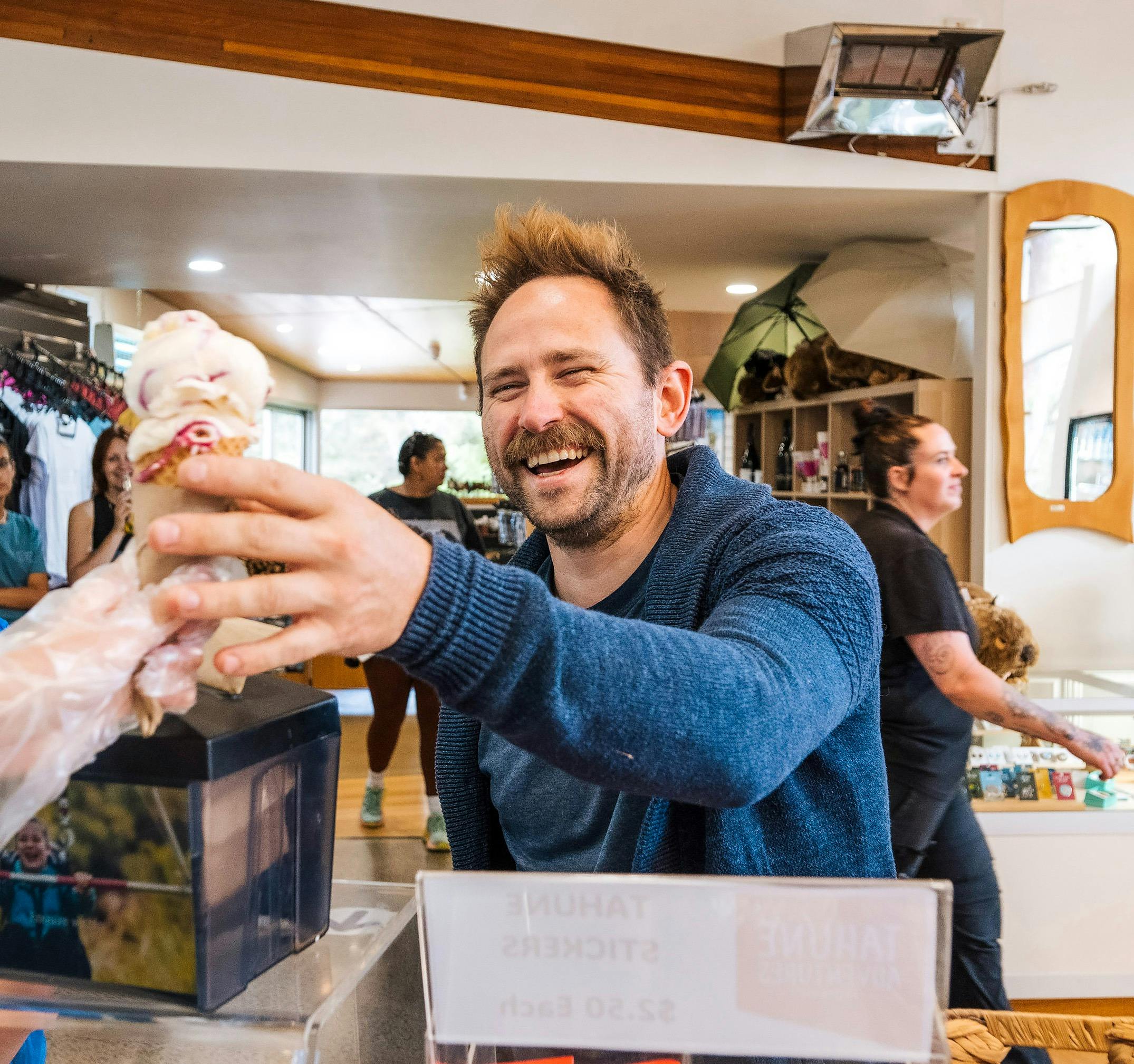 A very happy man taking a boysenberry icecream cone