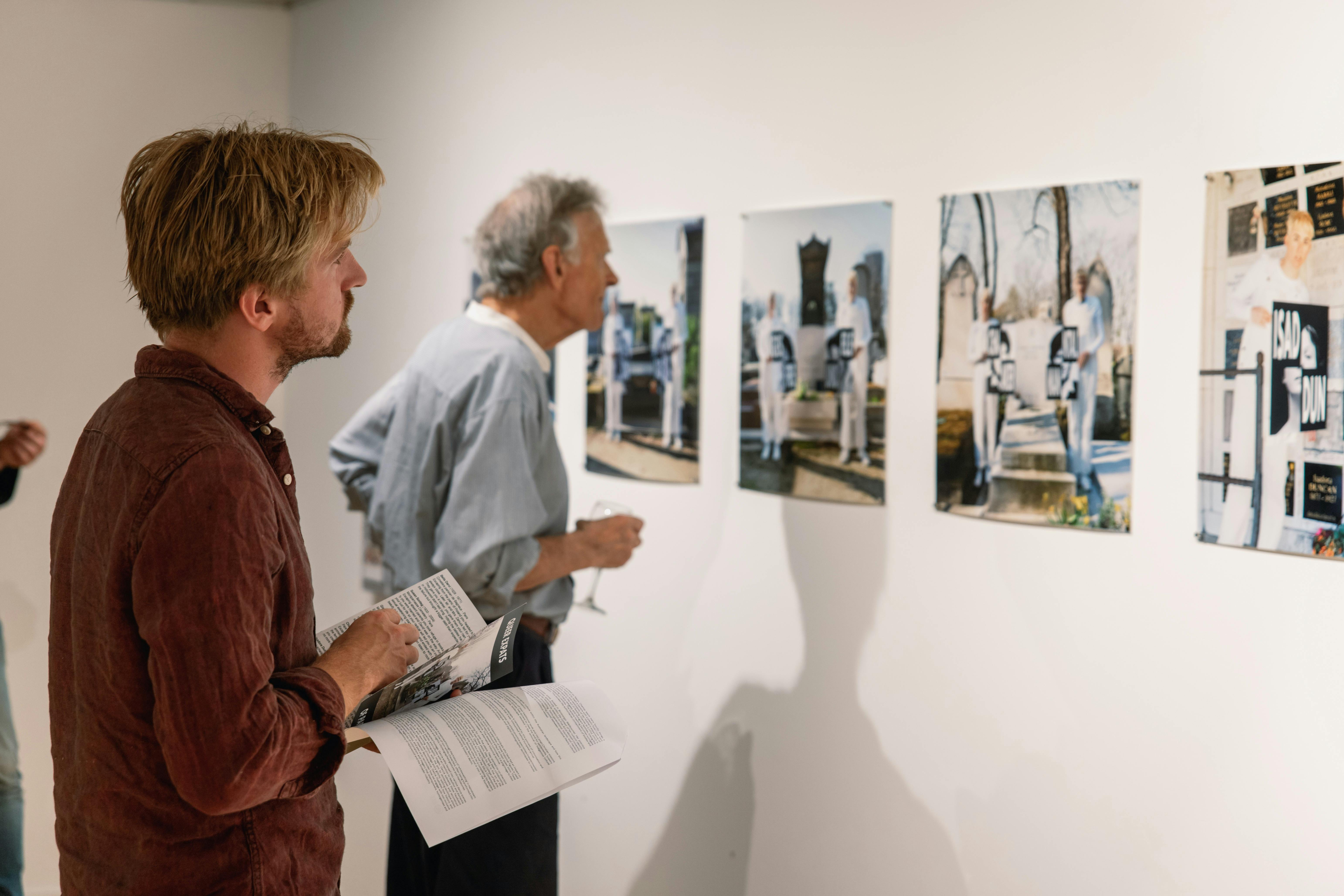 Two men look at photographs on the gallery wall