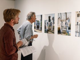 Two men look at photographs on the gallery wall