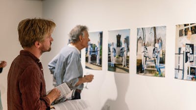 Two men look at photographs on the gallery wall