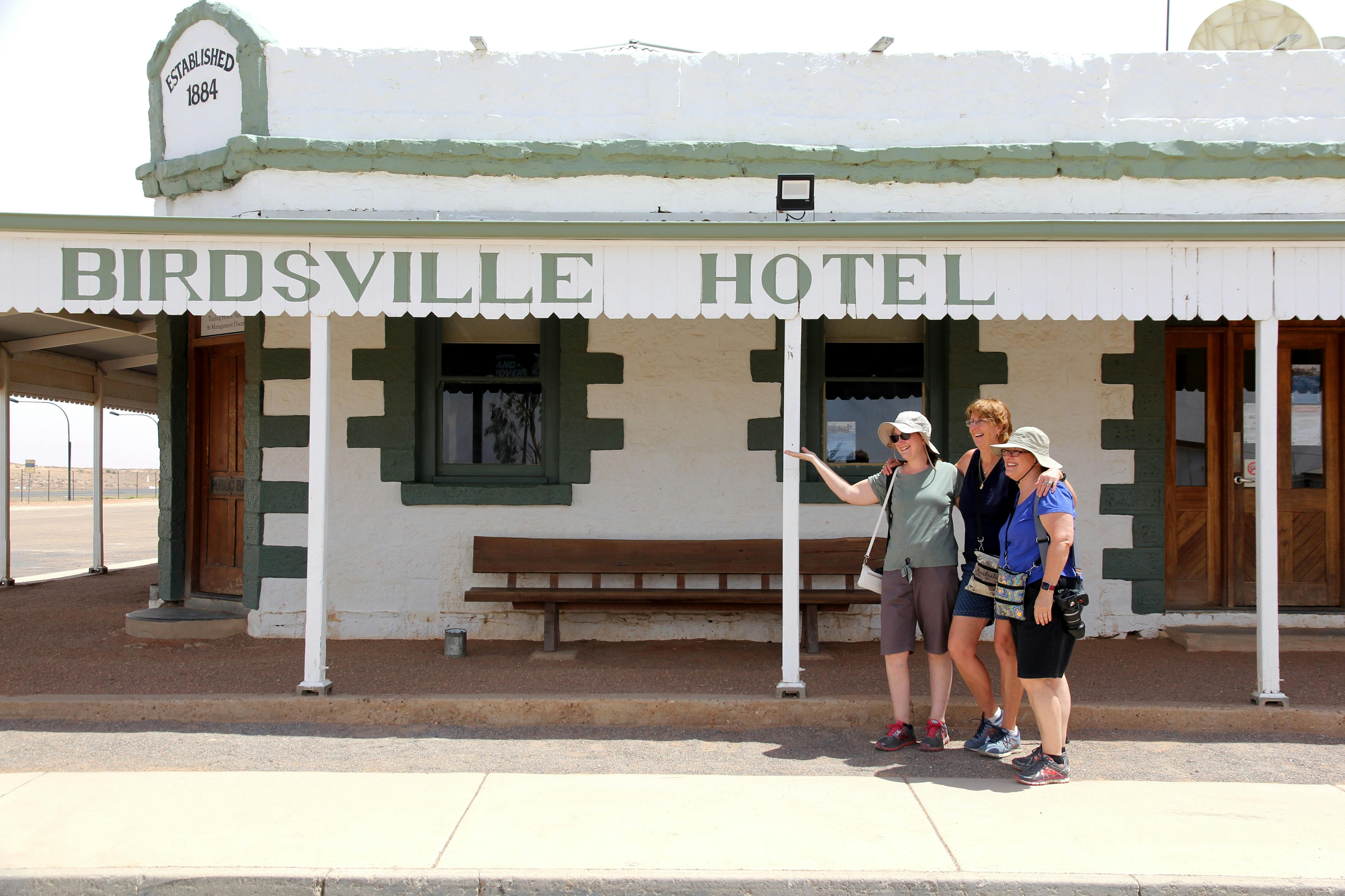 Three women posing for a photo outside the Birdsville Hotel