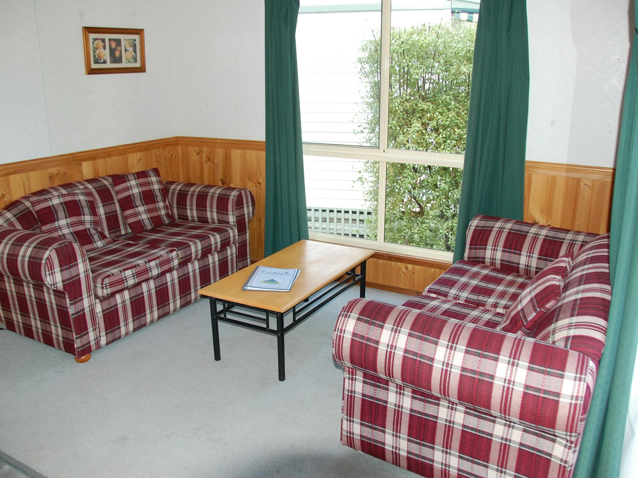Two red and white checkered couches in a room with a large window
